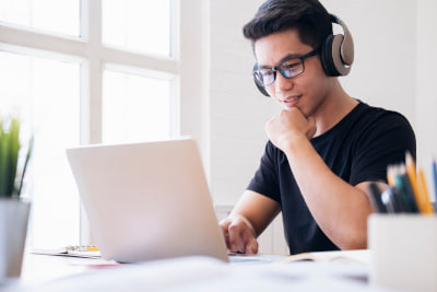 A smiling student sitting at a desk with a laptop and flags